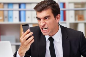 Angry businessman screaming unto his smart phone