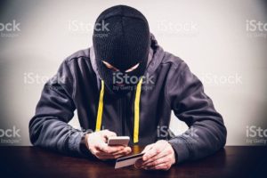 Masked criminal stealing mobile phone payment information and passwords